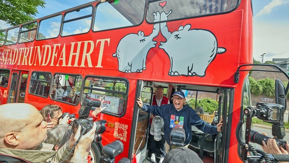 Otto Waalkes steht während der Einweihung eines Ottifanten-Doppeldeckerbusses an den Hamburger Landungsbrücken in der Tür des Busses. © picture alliance / dpa Foto: Georg Wendt