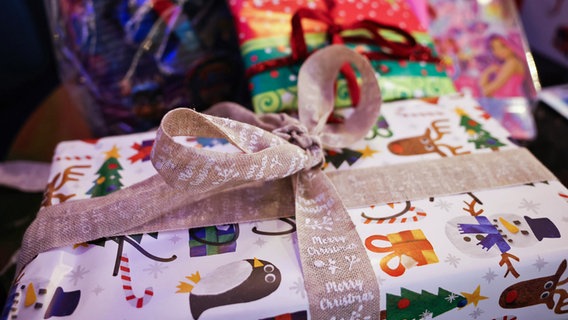 Weihnachtlich verpackte Geschenke liegen auf einem Tisch. © dpa Foto: Christian Charisius