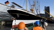 Das Segelschiff "Peking" liegt vor dem Ausdocken in der Peters Werft, Arbeiter stehen am Pier. © picture alliance / dpa Foto: Carsten Rehder