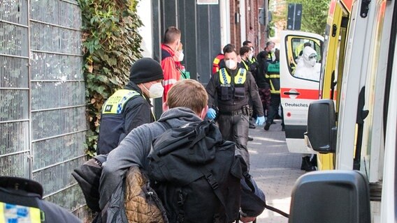 Bewohner der Obdachlosenwohnunterkunft Pik As gehen, begleitet von Polizisten zu Bussen von Hilfsorganisationen. Nach einem Corona-Ausbruch unter Obdachlosen sind 19 Bewohner der Unterkunft in Quarantäne gebracht worden. © picture alliance / dpa Foto: Daniel Bockwoldt