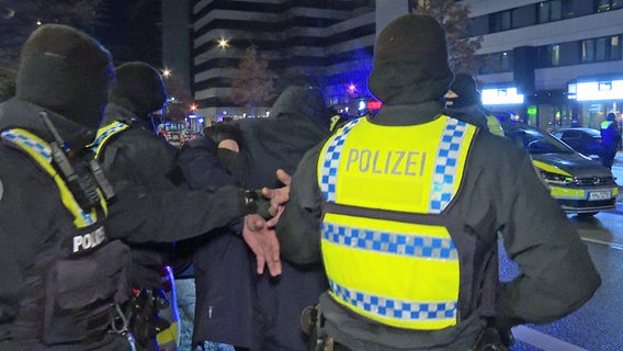 Polizisten nehmen einen Verdächtigen fest. Vorher ist ein Mann durch Schüsse vor einem Lokal am Hamburger Hansaplatz verletzt worden. © picture alliance / dpa 