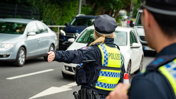Eine Polizistin weißt Autos nahe dem Volksparkstadion an einer von der Polizei gesperrten Zufahrt den Weg. © picture alliance/dpa Foto: Jonas Walzberg