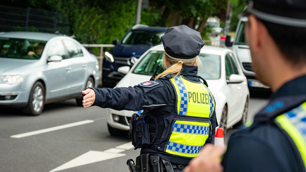 Eine Polizistin weißt Autos nahe dem Volksparkstadion an einer von der Polizei gesperrten Zufahrt den Weg.