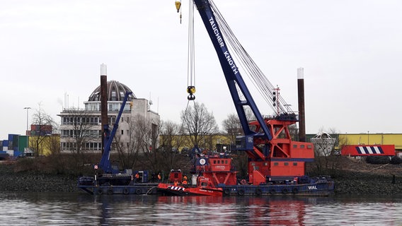 Ein Schiff, das in der Nähe der Köhlbrandbrücke gesunken ist, wird mit einem Kran aus dem Wasser geborgen. © picture alliance / dpa Foto: Rabea Gruber