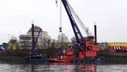 Ein Schiff, das in der Nähe der Köhlbrandbrücke gesunken ist, wird mit einem Kran aus dem Wasser geborgen. © picture alliance / dpa Foto: Rabea Gruber