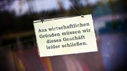 Ein Schild mit der Aufschrift "Aus wirtschaftlichen Gründen müssen wir dieses Geschäft leider schließen". © picture alliance / CHROMORANGE Foto: Christian Ohde