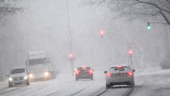 Fahrzeuge sind bei starkem Schneefall auf einer Hauptverkehrsstraße unterwegs. © Christian Charisius/dpa Foto: Christian Charisius