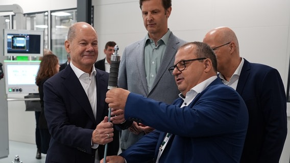 Eröffnung des Gigahubs für grüne Wasserstofftechnologie in Hamburg: Manager Jens Werner Schwarz (vorne, r.) zeigt Bundeskanzler Olaf Scholz (l.) einen Zuganker, der in einen sogenannten Stack gesteckt wird. © picture alliance / dpa Foto: Markus Brandt