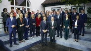 Bundeskanzler Olaf Scholz (vorne r, SPD) und Emmanuel Macron (l), Staatspräsident von Frankreich, sowie die deutschen und französischen Kabinettsmitglieder stehen während des Familienfotos im Hotel Louis C. Jacob zusammen. © picture alliance/dpa Foto: picture alliance/dpa | Marcus Brandt