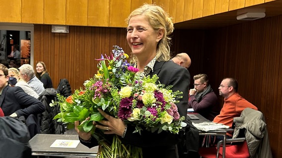 Bettina Schomburg (SPD) hält nach ihrer Wahl zur neuen Bezirksamtsleiterin in Hamburg-Nord mehrere Blumensträuße in der Hand. © NDR Foto: Anna-Lena Ehle