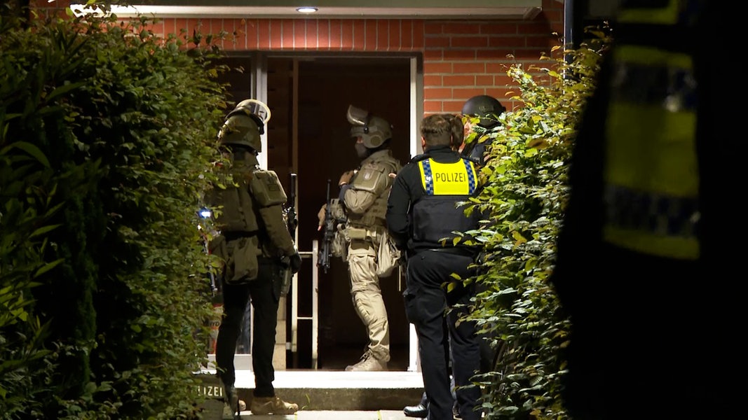Polizisten und Einsatzkräfte des SEK stehen nachts im Eingang eines Mehrfamilienhauses im Hamburger Stadtteil Rahlstedt.