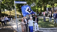 Stefanie von Berg (l-r), Bezirksamtsleiterin Altona, Peter Tschentscher (SPD), Erster Bürgermeister und Präsident des Senats der Freien und Hansestadt Hamburg, Stefan Kuntz, Vorstand Hamburger SV, Ilka Seeler (vorn), Witwe von Fußballlegende U. Seeler, und Kaja Steffens, stellvertretende Vorsitzende der Bezirksversammlung enthüllen bei einer Straßenumbenennung am Volkparkstadion das neue Straßenschild „Uwe-Seeler-Allee“. © picture alliance/dpa Foto: Christian Charisius