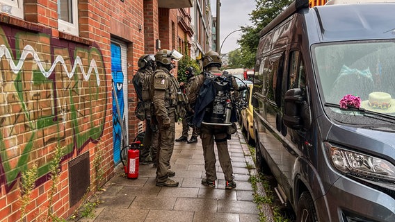 Schwer bewaffnete Polizisten des SEK stehen vor einem Wohnhaus in Hamburg Ottensen. © NDR Foto: Elias Bartl