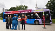 Ole Kampovski (NDR), Kerstin Hintze (Sesame Workshop Europe), Raimund Brodehl und Melanie Ruhl (HVV) präsentieren gemeinsam mit Krümelmonster den neuen "Sesamstraße"-Bus. © NDR/hvv/obs 