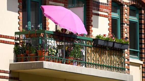 Ein rosa Sonnenschirm steht auf einem Balkon in Hamburg. © CHROMORANGE Foto: Christian Ohde