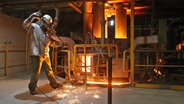 Ein Schmelzer misst die Temperatur in einem Pfannenofen in der Stahlwerkshalle von ArcelorMittal in Hamburg. © picture alliance / dpa Foto: Christian Charisius