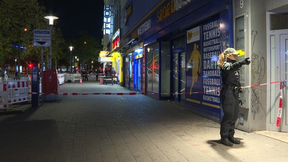 Eine Polizistin steht an einem mit Flatterband abgesperrten Abschnitt des Steindamms in Hamburg. Dort hat ein bislang unbekannter Täter einen Mann angeschossen. © picture alliance / dpa 