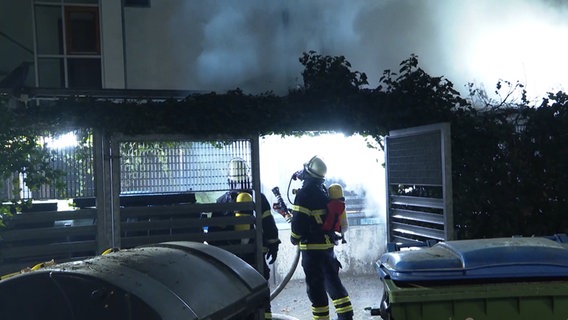 Zwei Feuerwehrleute löschen einen brennenden Papiercontainer vor einer Familieneinrichtung in Eimsbüttel. © TeleNewsNetwork Foto: TeleNewsNetwork