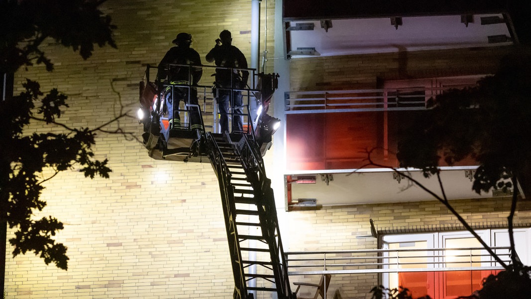 Einsatzkräfte stehen auf einer Drehleiter an einem Hochhaus im Stadtteil Altona und suchen die Fassade nach Beschädigungen durch Schüsse ab.