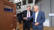 Hamburgs Bürgermeister Peter Tschentscher (r.) und Helge Heegewaldt, Präsident des Bundesamtes für Seeschifffahrt und Hydrographie (BSH), bei einem Rundgang zur Ausstellungseröffnung "100 Jahre Sturmflutwarndienst" im BSH. © picture alliance / dpa Foto: Christian Charisius