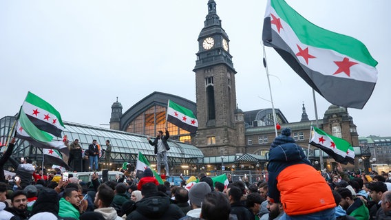 Zahlreiche Menschen feiern am Hachmannplatz am Hauptbahnhof den Sturz von Syriens Machthaber Assad. © Bodo Marks/dpa 