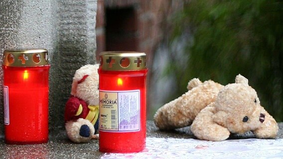 Kerzen und Kuscheltiere liegen in Hamburg-Wilhelmsburg vor dem Haus, in dem die Leiche der kleinen Lara gefunden wurde. © dpa Foto: Jens Ressing