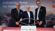 Peter Tschentscher (M., SPD), Erster Bürgermeister von Hamburg, steht mit Toralf Haag (l.), Vorstandsvorsitzender der Aurubis AG, und Michael Prinz, Geschäftsführer der Hamburger Energiewerke, an einem überdimensionalen Ventil nach dem symbolischen Start der Wärmelieferung mit industrieller Abwärme. © picture alliance / dpa Foto: Marcus Brandt