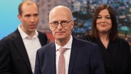 Peter Tschentscher (SPD) steht vor Dennis Thering (CDU) und Katharina Fegebank (Grüne) in einem Fernsehstudio am Abend nach der Bürgerschaftswahl. © picture alliance/dpa 