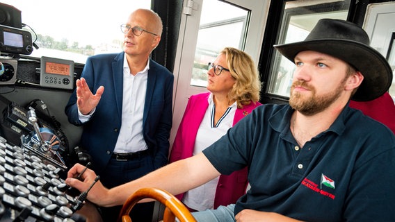 Hamburg Bürgermeister Peter Tschentscher (l.) und Bundesentwicklungsministerin Svenja Schulze auf einer Barkasse im Hamburger Hafen. Rechts daneben Schiffsführer Julian Zimmermann. © picture alliance / dpa Foto: Daniel Bockwoldt