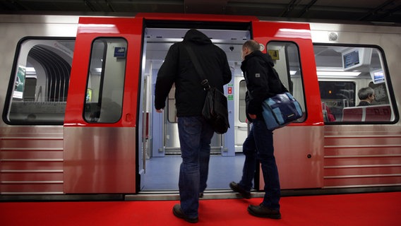 Zwei Männer steigen in Hamburg im Bahnhof Jungfernstieg in eine U-Bahn ein. © picture alliance / dpa Foto: Daniel Bockwoldt