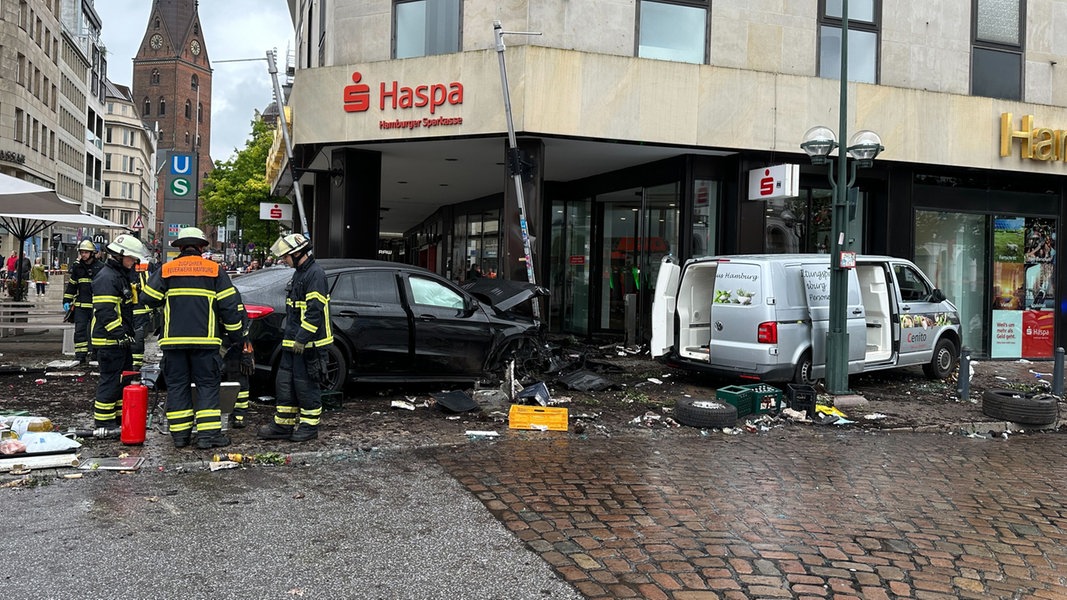 Helfer stehen an einem demolierten Auto vor einer Sparkasse am Hamburger Jungfernstieg. Bei einem Unfall wurden mehrere Menschen verletzt.