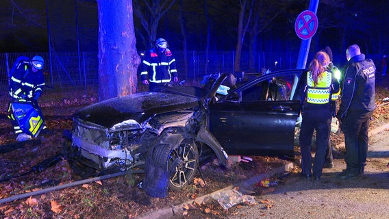 Einsatzkräfte der Polizei und Feuerwehr stehen nach einem schwerem Verkehrsunfall in der Kieler Straße in Hamburg an der Unfallstelle. © HamburgNews 