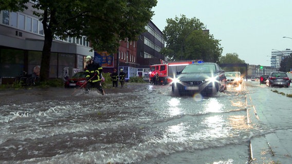 Autos fahren über eine durch Starkregen überflutete Straße in Hamburg Barmbek. © dpa/TNN | Steven Hutchings 