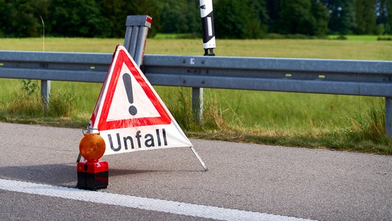 Ein Warndreieck mit der Aufschrift Unfall und einer Warnleuchte sichert eine Unfallstelle auf der Autobahn ab. © picture alliance Foto: Michael Bihlmayer