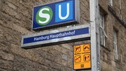 Ein gelbes Schild, das auf das geltende Waffenverbot hinweist, hängt unter dem Eingangsschild am Hamburger Hauptbahnhof neben den Logos von S-Bahn und U-Bahn. © picture alliance/dpa Foto: Niklas Graeber