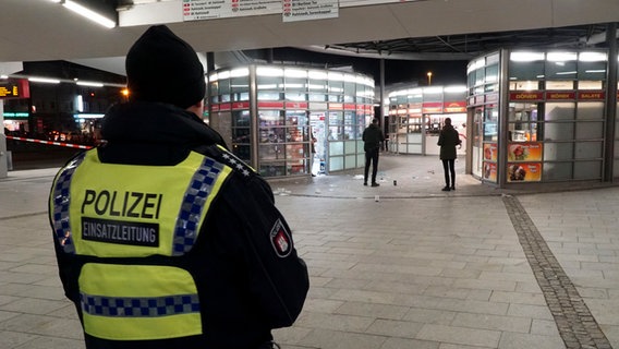 Ein Tatort am Bahnhof Wandsbek der abgesperrt ist. Zwei Männer sichern die Spuren, außerdem steht dort ein Polizist in Uniform. © picture alliance / ABBfoto Foto: picture alliance