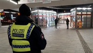 Ein Tatort am Bahnhof Wandsbek der abgesperrt ist. Zwei Männer sichern die Spuren, außerdem steht dort ein Polizist in Uniform. © picture alliance / ABBfoto Foto: picture alliance