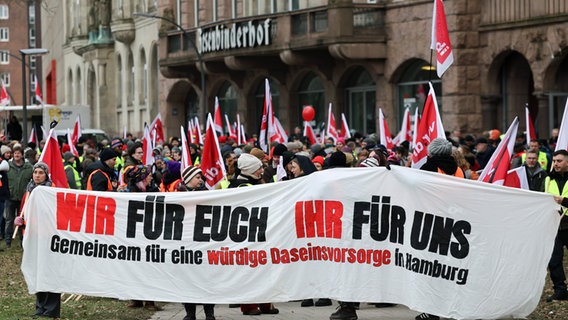 Teilnehmerinnen und Teilnehmer demonstrieren während eines Warnstreiks im öffentlichen Dienst vor dem Gewerkschaftshaus Besenbinderhof. © picture alliance/dpa Foto: Christian Charisius