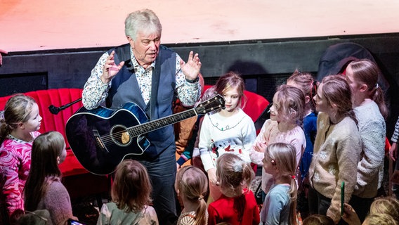 Der Sänger Rolf Zuckowski singt in Hamburg gemeinsam mit Kindern bei der Veranstaltung "Der große Weihnachtsbäckerei-Kindertag". © picture alliance / dpa Foto: Axel Heimken