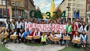 Mehrere Personen stehen für eine Unterschriftenübergabe beisammen. © NDR Foto: Anna Rüter