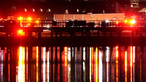 USA, Arlington: Beleuchtung von Einsatzfahrzeugen spiegeln sich im Potomac River in der Nähe des Ronald Reagan Washington National Airport. © Alex Brandon/AP/dpa 