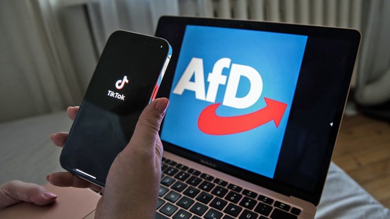 Ein Smartphone-Display zeigt das Logo der TikTok-App vor einem Laptop-Monitor mit dem AfD-Logo. © picture alliance / ZUMAPRESS.com | Michael Kuenne 