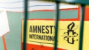 Das Logo von Amnesty International ist auf eine Wand gemalt. © picture alliance Foto:  Jumeau Alexis