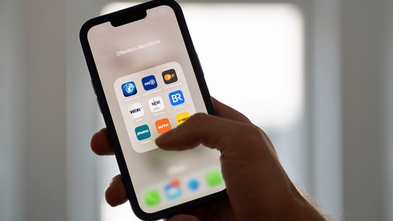 Eine Frau hält ein Smartphone, auf dessen Display verschiedene Apps des Öffentlich-rechtlichen Rundfunks angezeigt werden. © dpa picture alliance Foto: Alicia Windzio