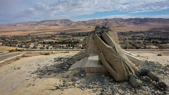 Syrien, Deir Atiyah: Eine Statue, die den verstorbenen syrischen Präsidenten Hafez Assad darstellt, und während des Aufstands, der das Assad-Regime im vergangenen Dezember stürzte, umgestürzt wurde, liegt in Trümmern auf einem Berg. © Ghaith Alsayed/AP/dpa 