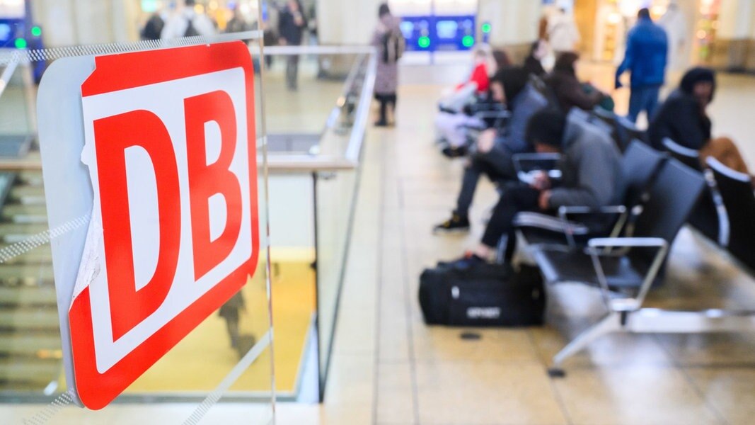 DB-Logo klebt während des Bahnstreiks im Hauptbahnhof Hannover - im Hintergrund warten Bahnkunden