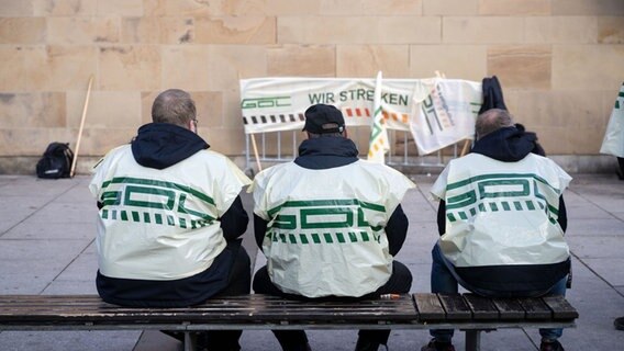 Teilnehmer eines Warnstreiks der Gewerkschaft Deutscher Lokomotivführer sitzen vor dem Hauptbahnhof auf einer Bank © picture alliance/dpa | Marijan Murat Foto: Marijan Murat