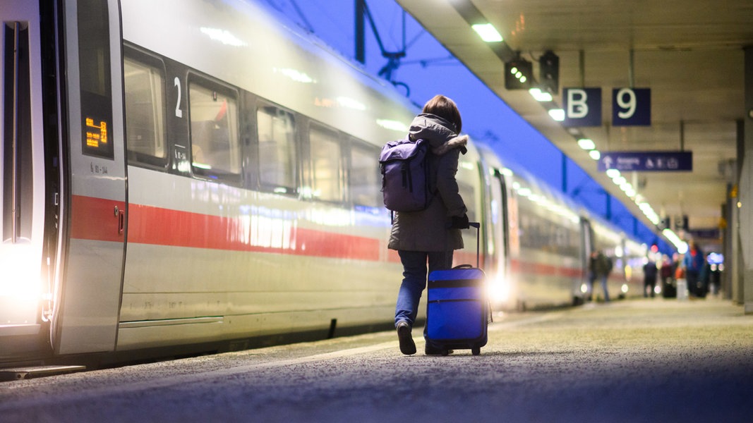 Eine Frau geht mit einem Koffer neben einem ICE im Hauptbahnhof Hannover. 