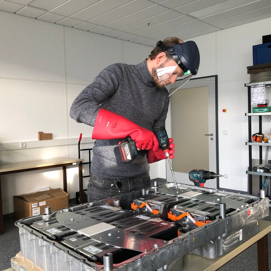 Geschäftsführer Lasse Bartels von LB Systems öffnet mit einem Werkzeug eine E-Auto-Batterie. © NDR Foto: Simon Hoyme