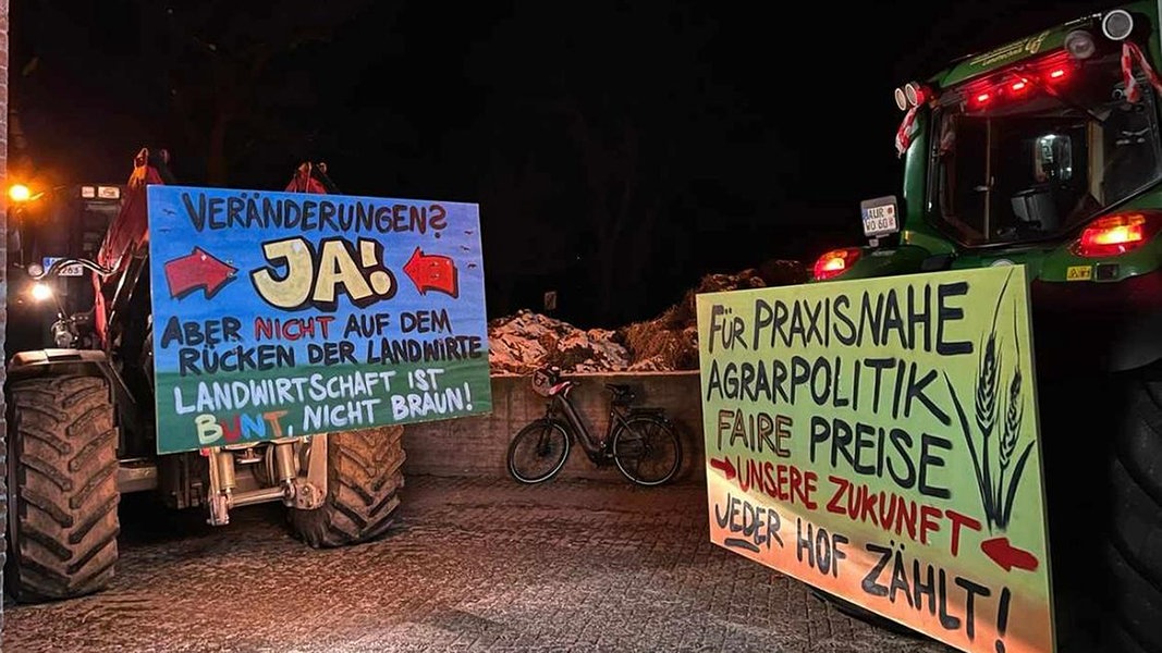 Zwei Traktoren mit Protestplakaten bei Nacht.